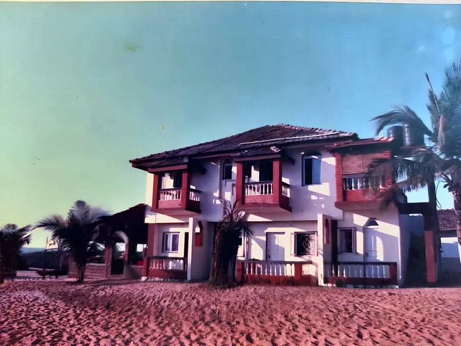 The hotel photographed from the beach in the 1980s, thatched umbrellas on the sand in front of it