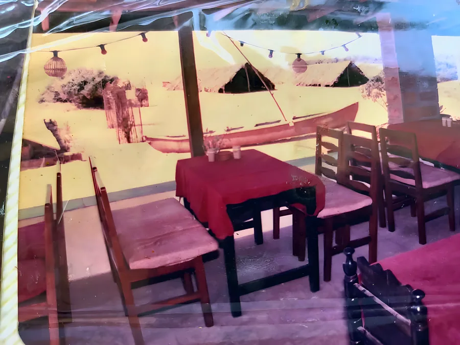 Red cloths, wooden chairs, a boat pulled up outside.