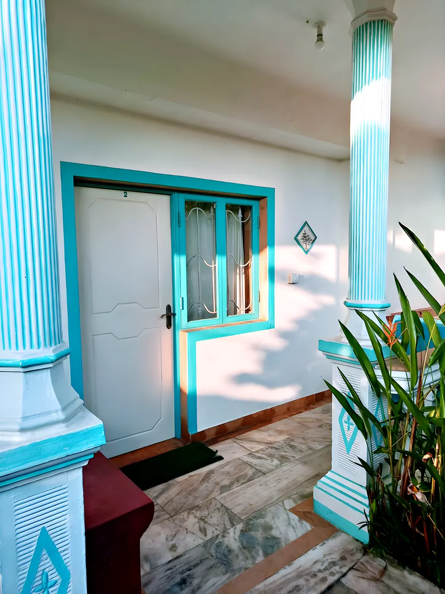 Turquoise-painted columns and a doorway with a terracotta floor.