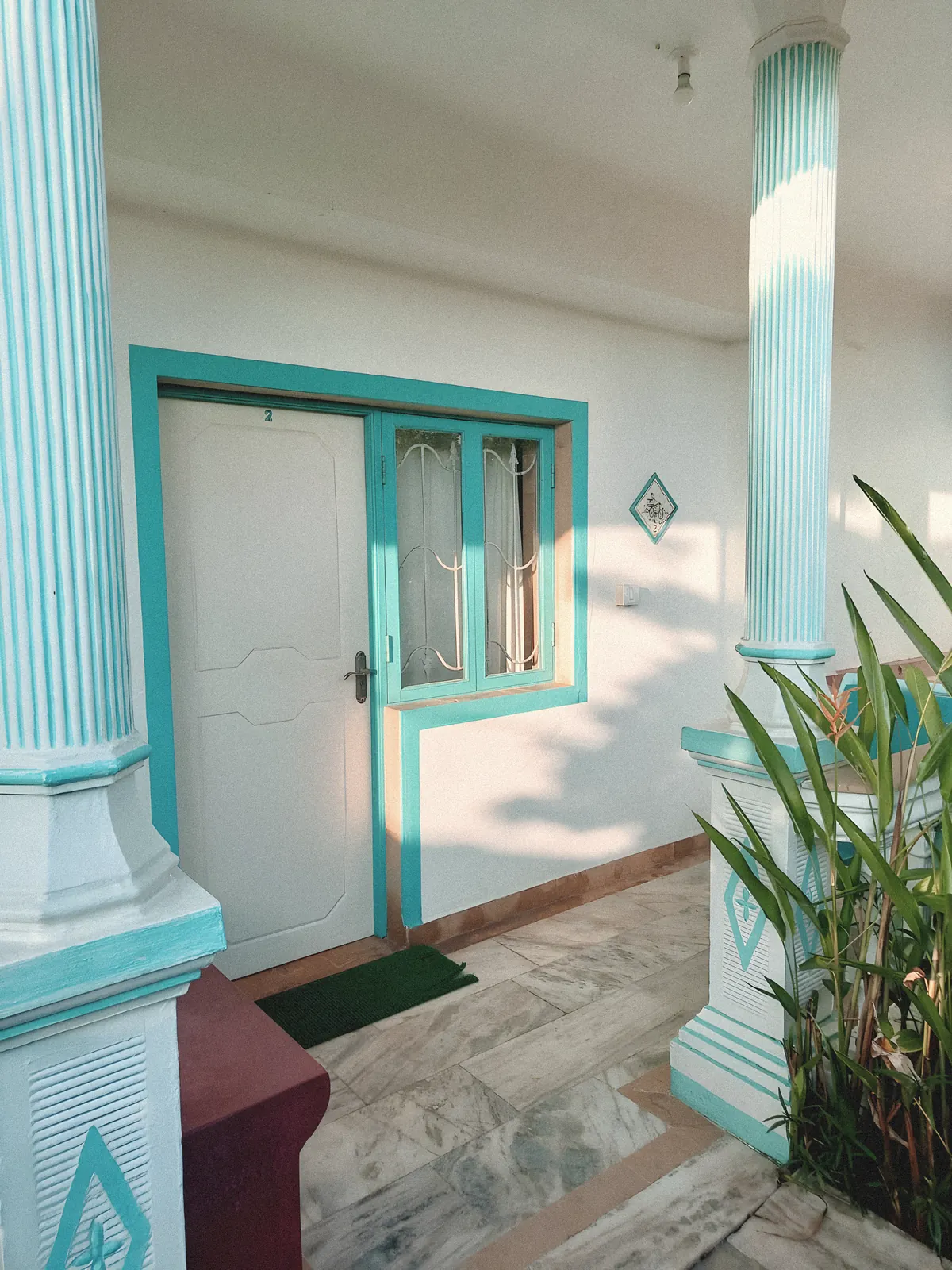 The turquoise columns and doorway of the house, treated as a faded print.